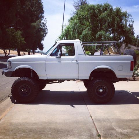 1995 Ford Bronco - This lifted SUV has a roll cage in the bed and large off-road tires.