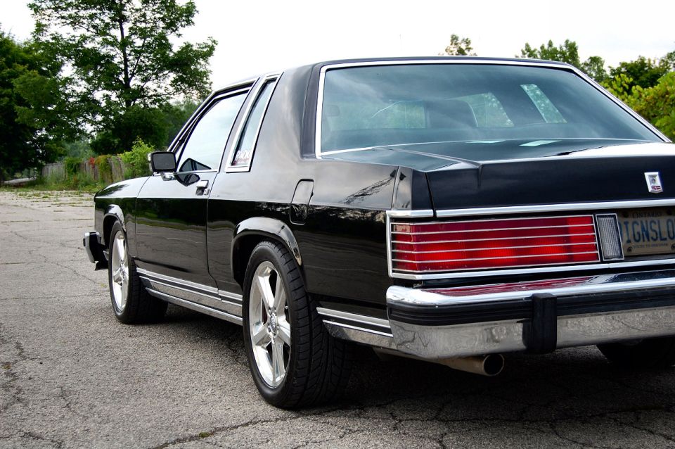 Black Mercury coupe rear 3/4 view with chrome wheels and red taillights