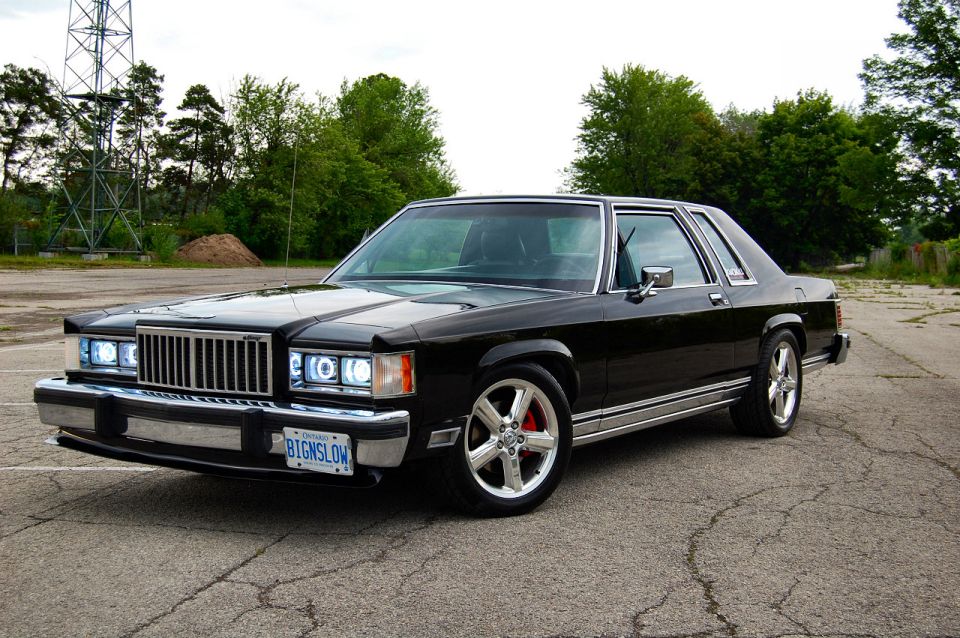 Black sedan with chrome trim and aftermarket wheels parked on asphalt