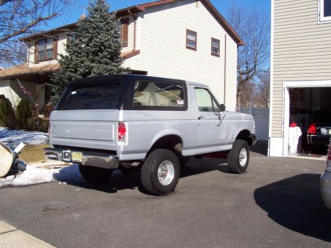 1990 Ford Bronco - Silver 1990 Ford Bronco with black top parked in a suburban driveway.