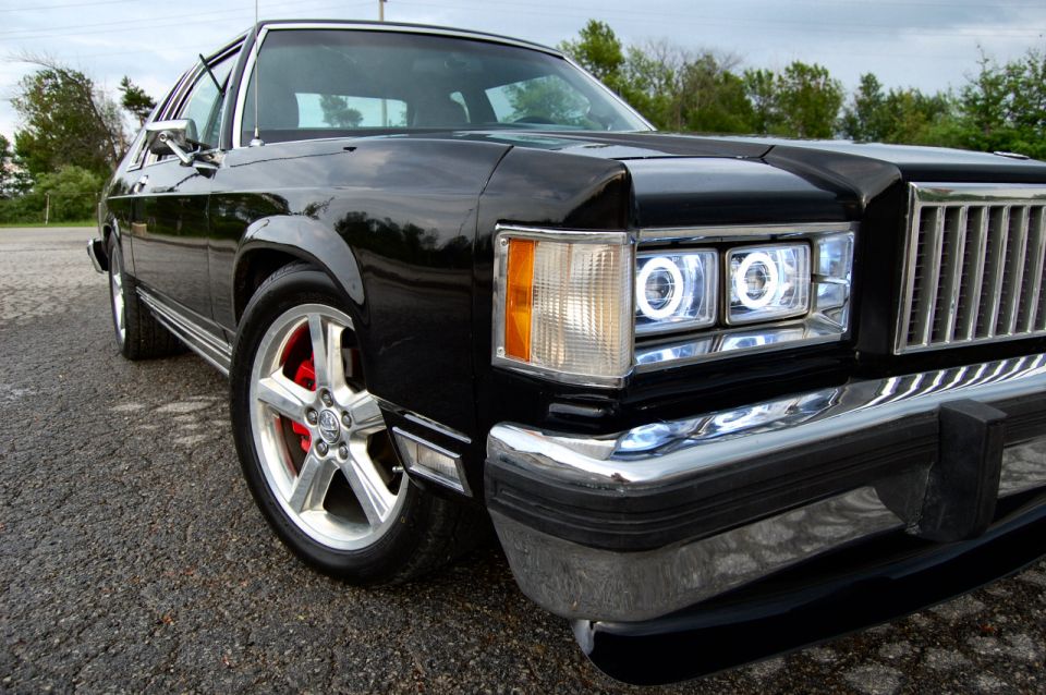 Front corner of a black sedan with custom halo headlights and red brake calipers