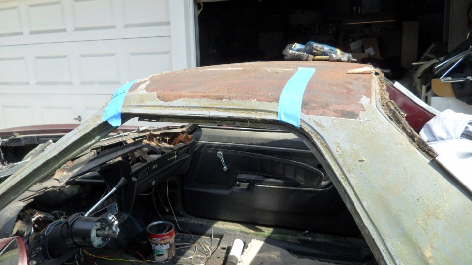 Interior of a car with a rusty roof, showing the dashboard and door panel