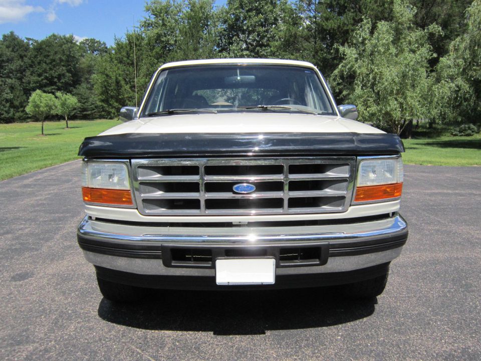 Front view of a white Ford Bronco with a black bug deflector and chrome grille