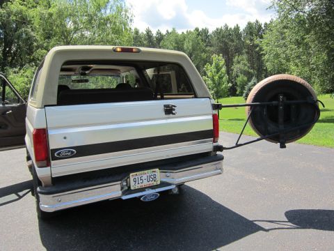 1994 Ford Bronco - This Ford Bronco features a rear-mounted spare tire and a two-tone paint scheme with a tan top.