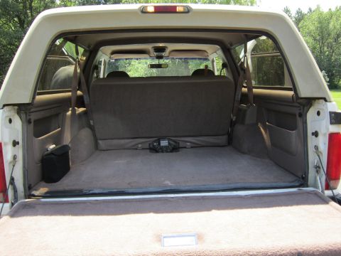 1994 Ford Bronco - Rear view of a white Ford Bronco's cargo area, showing the folded rear seat and interior details.