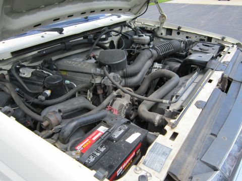 1994 Ford Bronco - The engine bay of a vehicle, showing the battery, hoses, and other engine components.