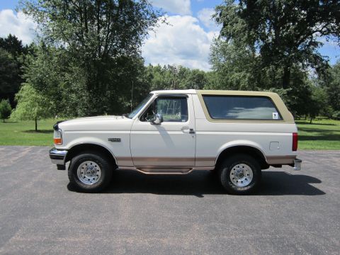 1994 Ford Bronco - This side view shows a white Ford Bronco with a tan removable top and brown accent trim.