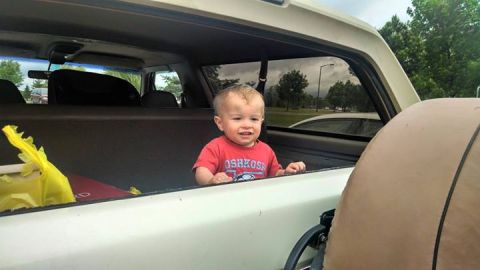 1994 Ford Bronco - A child sits in the cargo area of a 1994 Ford Bronco, looking out the rear window.