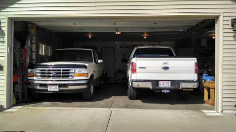 1994 Ford Bronco - Two Ford trucks, a Bronco and an F-150, are parked inside a garage.