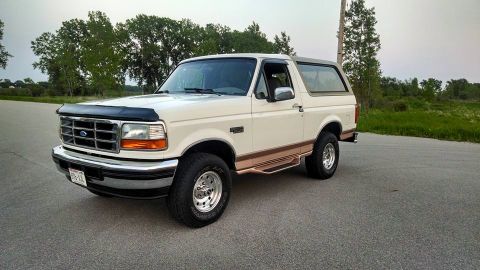 1994 Ford Bronco - This 1992 Ford Bronco is shown from the front three-quarter view, parked on a paved surface with a natural landscape behind it.