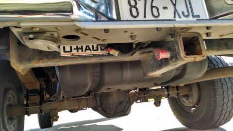 1994 Ford Bronco - Undercarriage view of a vehicle's rear bumper, trailer hitch, and fuel tank, with a U-Haul frame on the license plate.