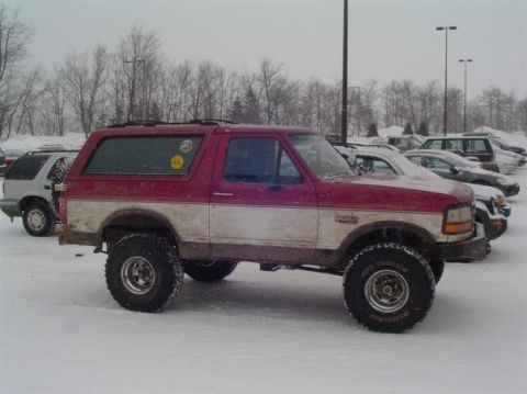 1994 Ford Bronco - Lifted 1994 Ford Bronco with red and white paint in a snowy parking lot.