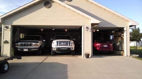 1994 Ford Bronco - Three vehicles are parked inside a garage, with two trucks in the foreground and a car in the background.