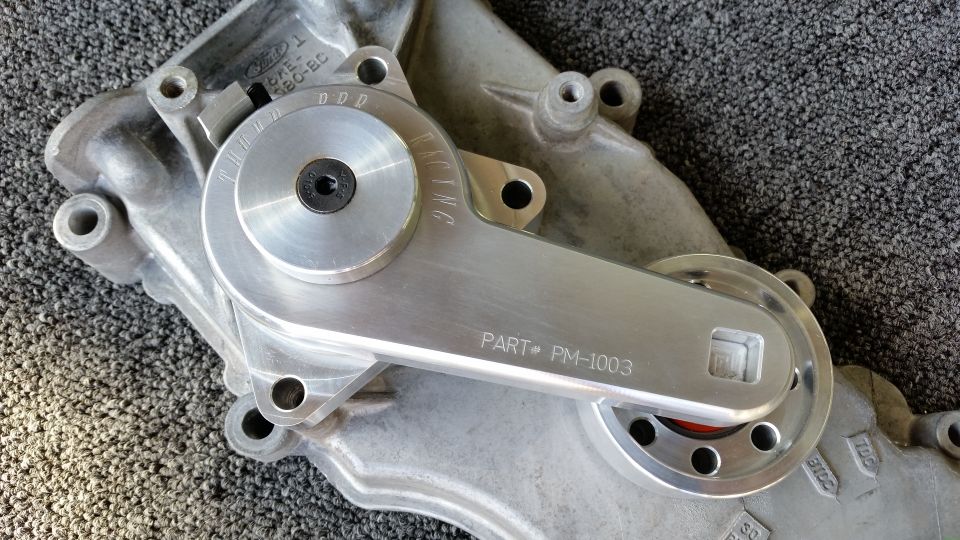 Machined aluminum timing cover part marked PM-1003 on carpet