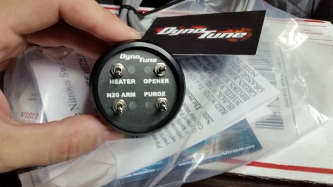 2003 Ford Crown Victoria - hand holds a round DynoTune control panel with toggle switches labeled HEATER, OPENER, N2O ARM and PURGE over packaging.
