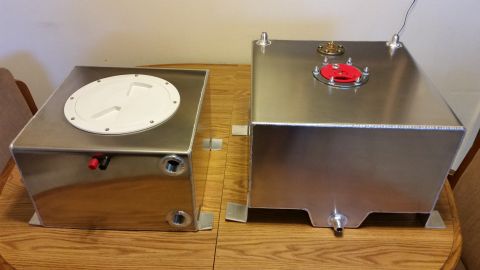 2003 Ford Crown Victoria - Two polished aluminum fuel cells, one with a white access cover and one with a red fuel cap, rest on a wooden table.
