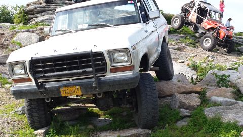 1979 Ford Bronco - White Ford Bronco navigating rocky terrain, with another off-road vehicle visible on the hill.