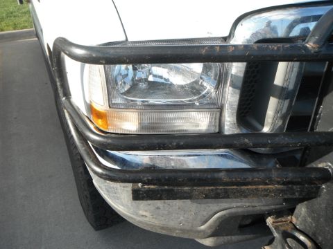 2000 Ford F-250 - Close-up of the front of a white Ford truck, a black bull bar over the grille and headlight.