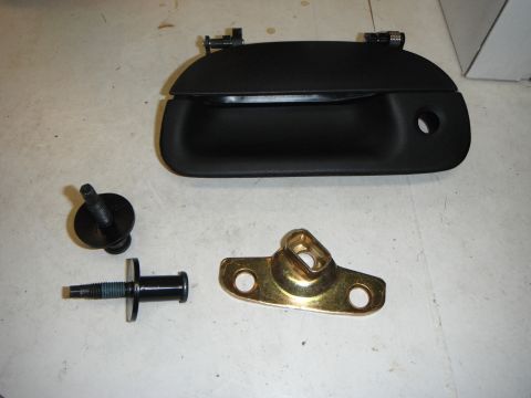 2000 Ford F-250 - A black door handle and associated hardware are laid out on a white surface.