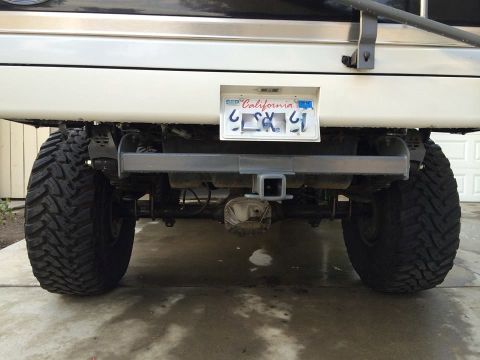 1995 Ford Bronco - This lifted SUV features large off-road tires and a trailer hitch, with a California license plate visible.