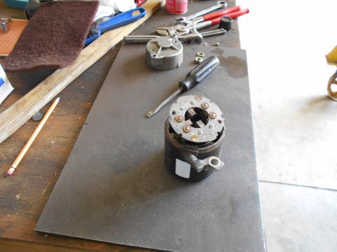 1992 Ford Bronco - A disassembled starter motor part sits on a metal plate on a workbench, surrounded by various tools.