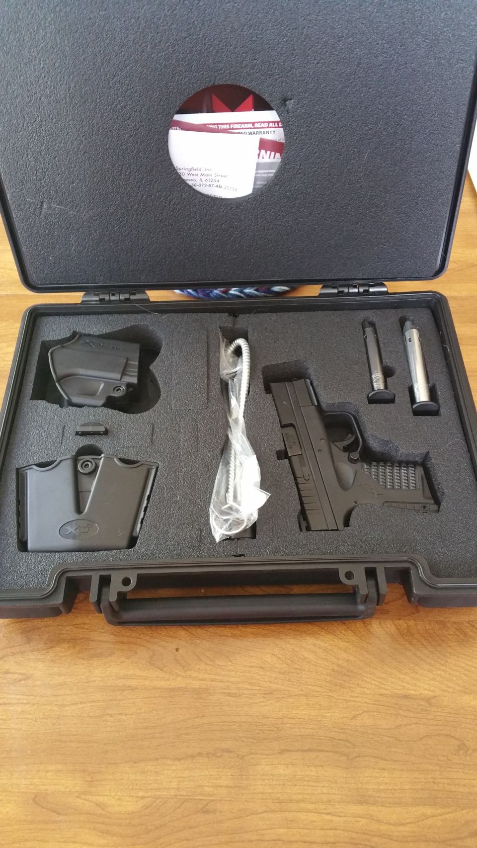 Black pistol with holster, magazine, and cleaning brush in a fitted case