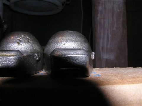 1993 Ford Bronco - Two metallic engine components are shown up close, resting on a workbench.
