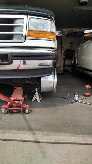 1994 Ford Bronco - Front view of a 1994 Ford Bronco being serviced in a garage, with a jack and jack stands visible.