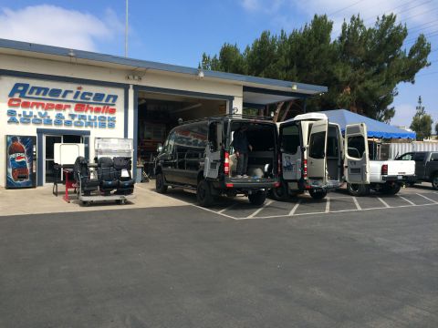 1997 Dodge 3500 - Multiple vans and a pickup truck are parked in front of a store selling camper shells and accessories.