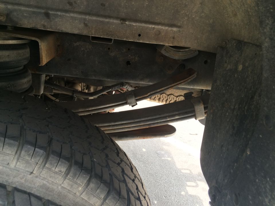 Underside of a truck showing leaf springs, tire, and frame