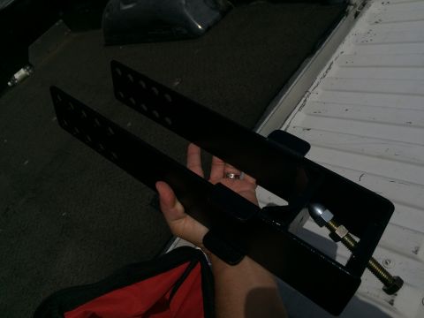 1997 Dodge 3500 - A black metal bracket with bolts is held in a person's hand inside a truck bed.