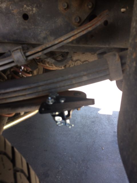 1997 Dodge 3500 - A close-up view of a metal bracket attached to the leaf spring assembly of a truck.