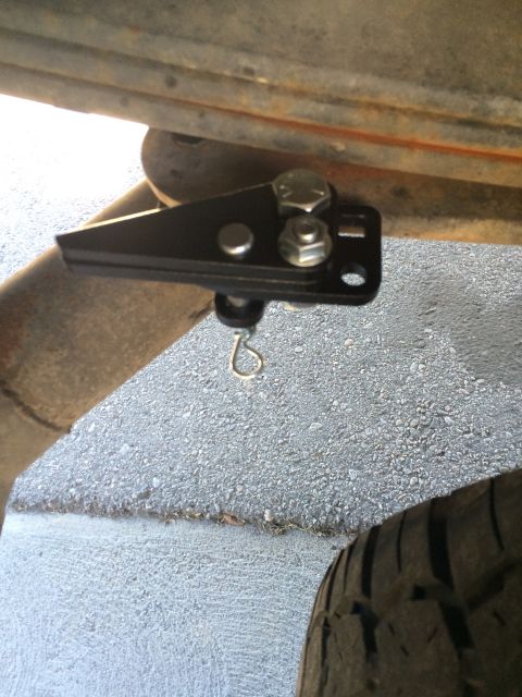 1997 Dodge 3500 - A close-up view of a black metal bracket and hardware mounted to a vehicle's undercarriage, near the exhaust and tire.
