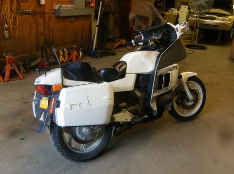 2000 Ford E350 - A white touring motorcycle with saddlebags is parked inside a garage, with a tan SUV in the background.