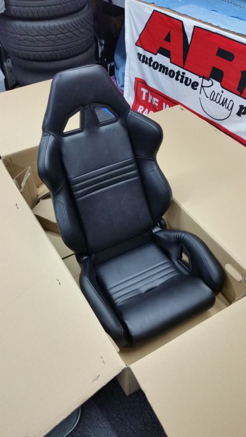 2003 Ford Crown Victoria - black leather racing-style bucket seat with side bolsters sits in an open cardboard box in front of an ARP banner.