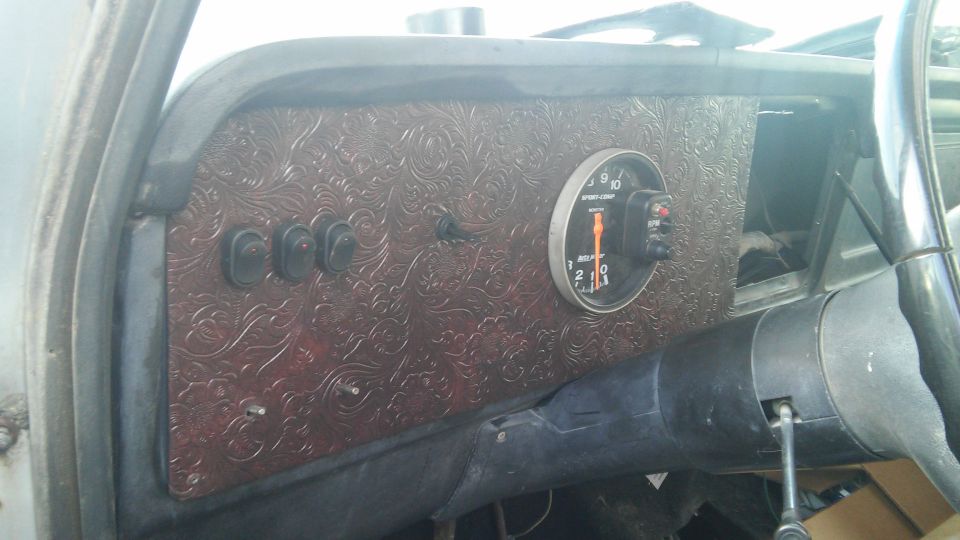 Custom embossed dark red dash panel with rocker switches and Auto Meter Sport-Comp tach in a 1979 Ford Bronco