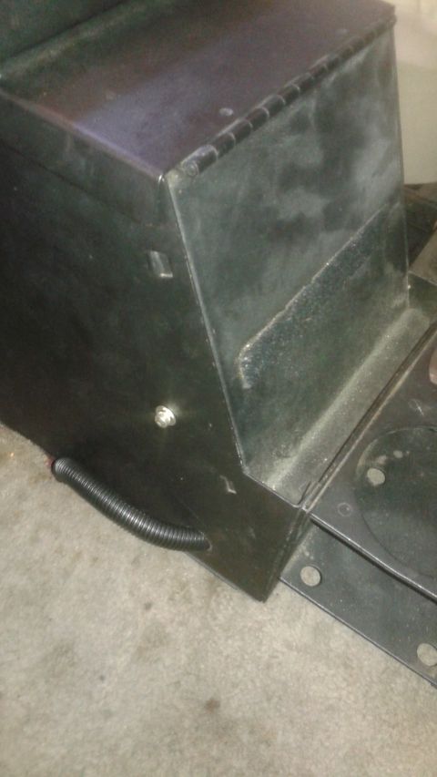 1996 Ford Bronco - A close-up view of a black metal storage box with a hinged lid, mounted on a vehicle. A corrugated black tube exits the box near the bottom…