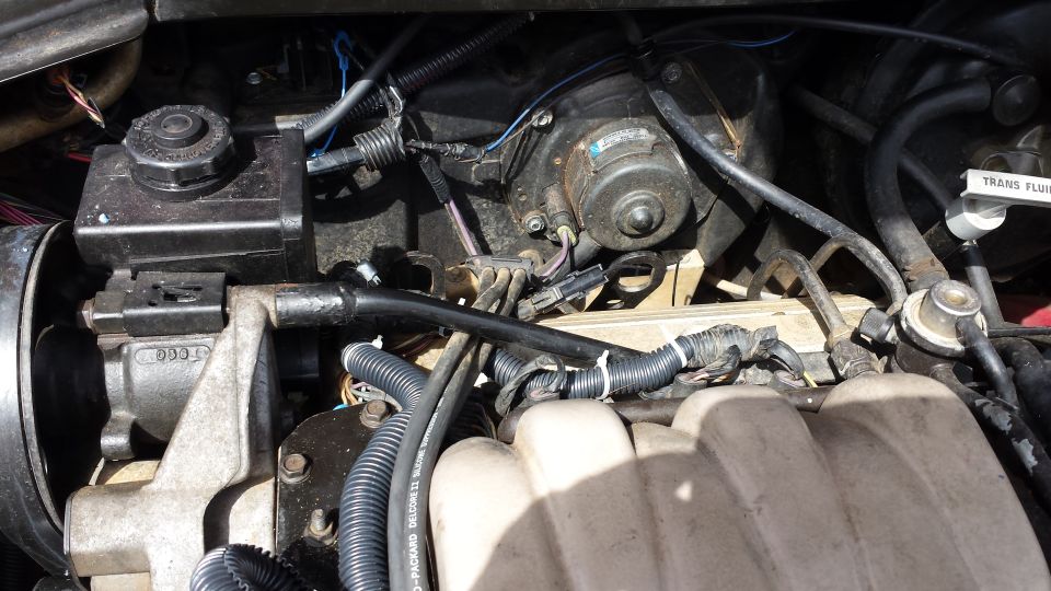 Engine bay of a 1991 Buick Reatta, showing power steering fluid reservoir, blower motor, and fuel system components.