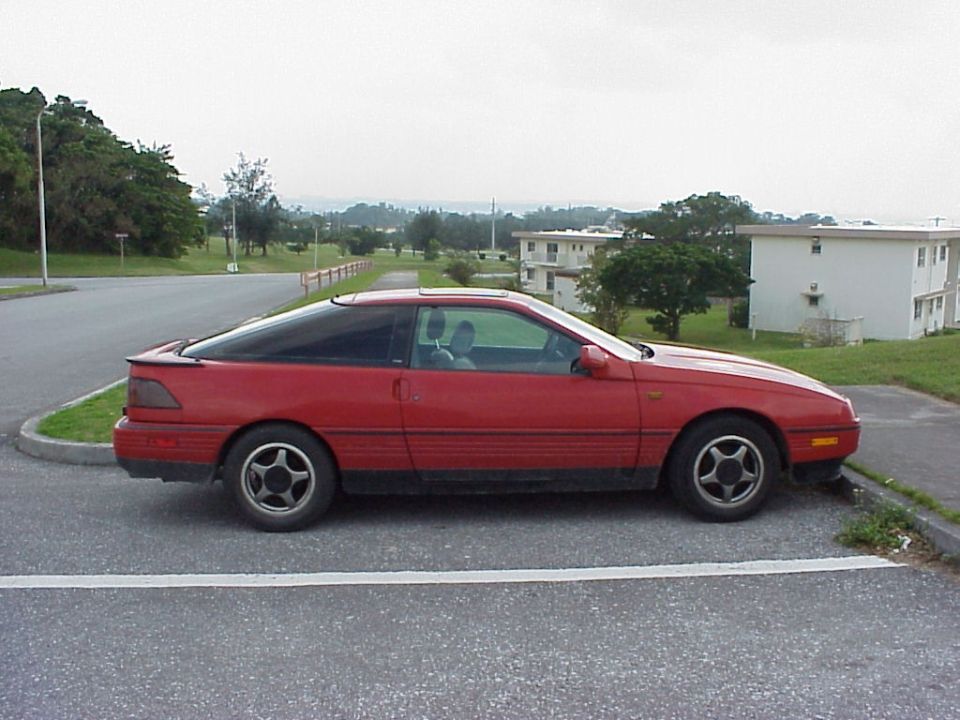 Red 1988 Ford Probe parked on the side of the road.