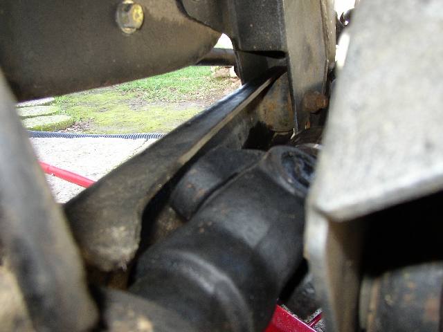 Underside view of greasy black suspension components with red hose
