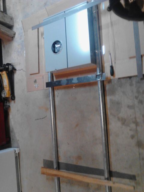 1989 Ford Bronco - A close-up view of a metal electrical box mounted on a metal frame with wooden supports. A screwdriver is visible to the right of the box.