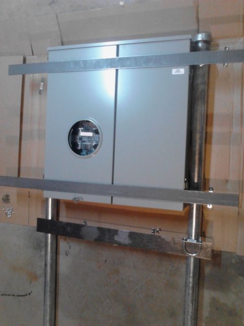 1989 Ford Bronco - A gray electrical meter box is mounted on a wall with metal bracing and conduit pipes. The meter has a circular glass window showing intern…