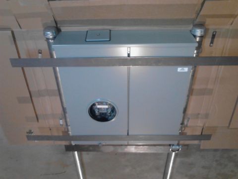 1989 Ford Bronco - A large gray electrical panel with a meter visible in the center is mounted on a wall, supported by metal brackets and pipes. The panel is…
