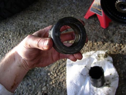 1989 Ford Bronco - A greasy bearing race is held by a dirty hand, with a tool on a paper towel in the background.