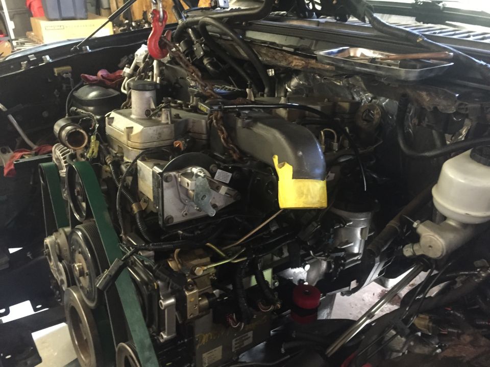 2003 Ford Excursion engine bay with engine lifted by hoist