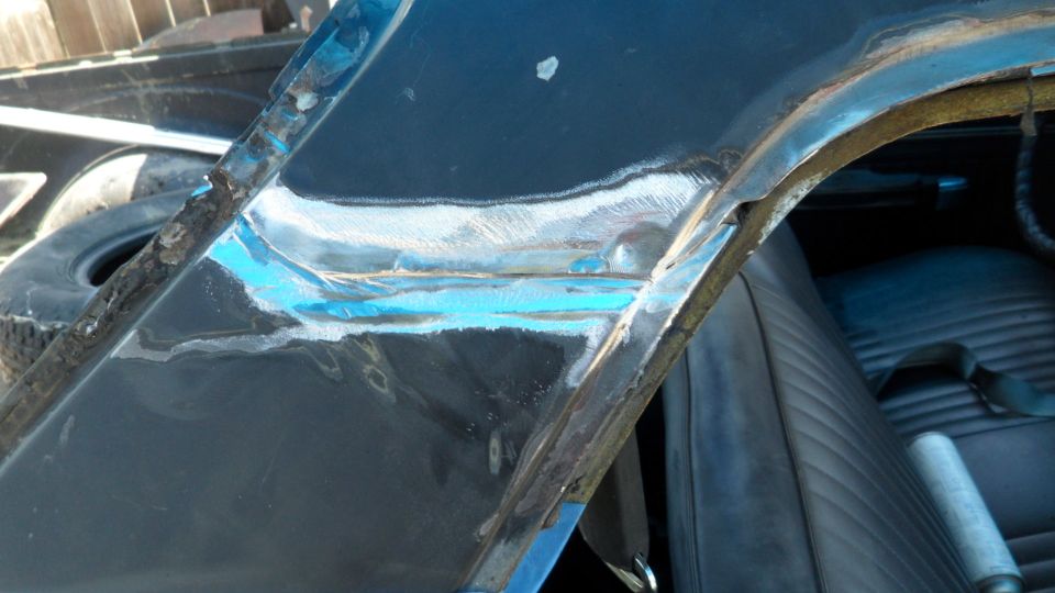 Close-up of a classic car's A-pillar and roofline with rust repair and primer.