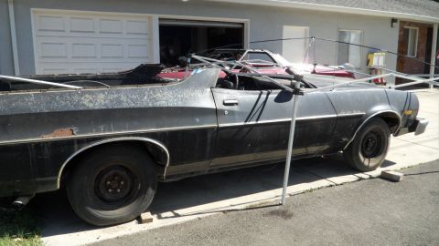 1972 Ford Ranchero - A weathered Ford Ranchero sits in front of a garage with another vehicle visible inside.