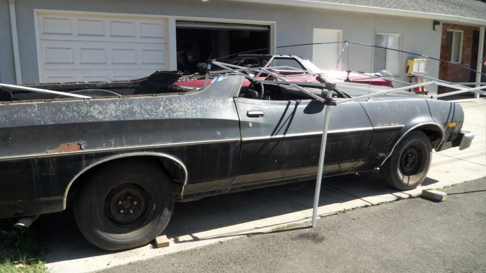 Side view of a black Ford Ranchero with a red car behind it in a driveway