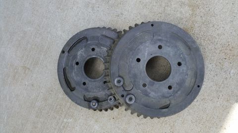 2015 Chevrolet new - Two metal gears, likely engine components, are shown side-by-side on a concrete surface.