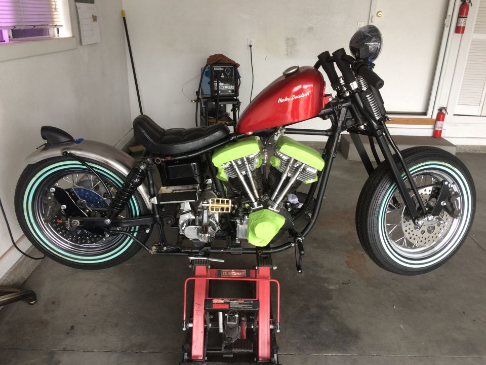 Red Harley-Davidson motorcycle on a red lift, with green engine covers and chrome fenders